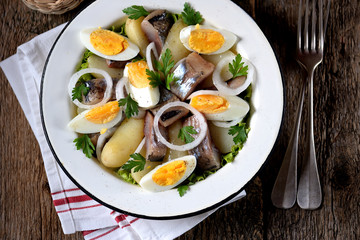 Salad from light-salted herring, boiled potatoes, eggs and onions with olive oil and lemon juice. Rustic style.