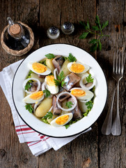 Salad from light-salted herring, boiled potatoes, eggs and onions with olive oil and lemon juice. Rustic style.