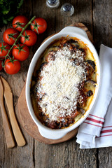 Baked Eggplants with mozzarella, parmesan cheese, tomato sauce and breadcrumbs on an old wooden background. Rustic style.