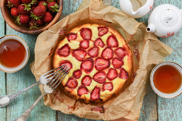 Sweet rustic strawberry pie in baking paper with fresh berries and tea