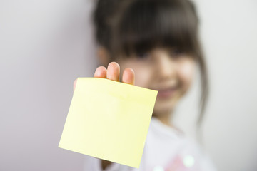 Hand holding yellow sticky note. Little girl with yellow stick note space 