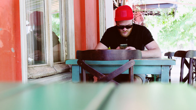 Beautiful ginger bearded man in red peaky cap is sitting on the