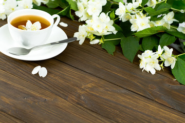 Tea with jasmine in a white cup on a wooden table.