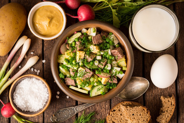 Okroshka. Traditional Russian summer cold yogurt soup in bowl on wooden background.