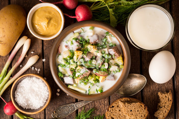 Okroshka. Traditional Russian summer cold yogurt soup in bowl on wooden background.