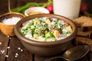 Okroshka. Traditional Russian summer cold yogurt soup in bowl on wooden background.