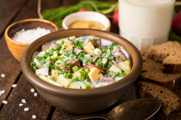 Okroshka. Traditional Russian summer cold yogurt soup in bowl on wooden background.