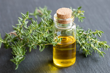 A bottle of essential oil with fresh thyme leaves