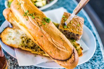 Macro closeup of large pieces of garlic bread in restaurant on plate with knife