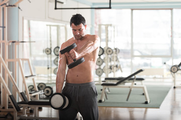 Fototapeta na wymiar Athlete Exercising Shoulders With Dumbbells