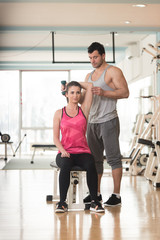 Gym Coach Helping Woman On Triceps Exercise