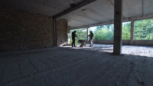 Two men in uniform attacking terrorists and freeing hostage inside of ruined building.