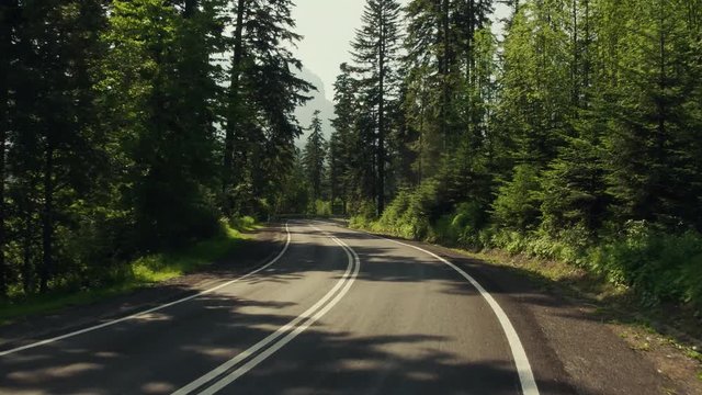 Car road bend in mountainuos forest and speed limit sign. 4K gimbal stabilized travelling shot