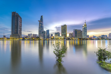 Fototapeta na wymiar Ho Chi Minh City, Vietnam - June 15th, 2017: Riverside City sunrays clouds in the sky at end of day brighter coal sparkling skyscrapers along beautiful river in Ho Chi Minh City, Vietnam