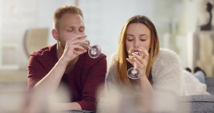 Young couple in love lying on sofa drinking wine and kissing