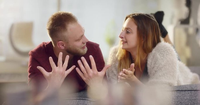 Young attractive couple in love lying on sofa and chatting