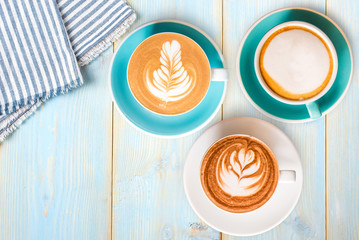 Three Coffee cups top view on wood table with tablecloth.