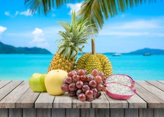 Fruit on wood table against blurred beach background. Summer concept,