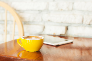 Coffee cup with tablet computer on wood table.