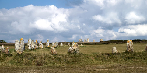 Alignment of megaliths in field with stone tower in background, in Camaret-sur-mer (France-Brittany)