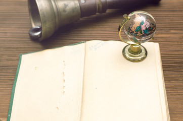 Globe, school bell and open vintage book on the wooden table. Education concept.