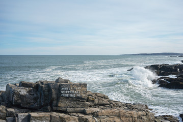 Writing on rock with waves crashing in background