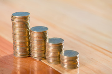 Increasing columns of coins, piles of gold coins arranged as a graph on wooden table. vintage tone.
