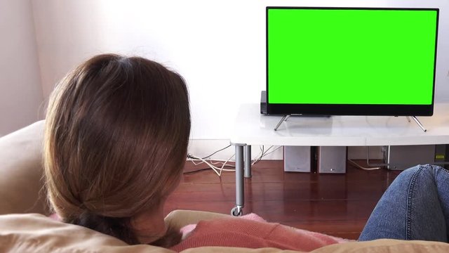 Girl Relaxed At Home Watching Television Green Screen. Young woman watching television green screen. Shot behind models shoulders