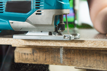 Close-up electric jigsaw for wood sawing a piece of wood