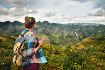 Hipster woman traveler with backpack enjoying beautiful view of mountains