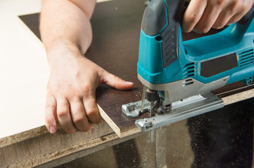 Close-up carpenter working with an electric jigsaw