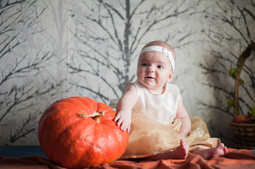 Mimicry of a small child. A little girl in a beautiful dress and a pumpkin. Child and pumpkin, autumn photography.