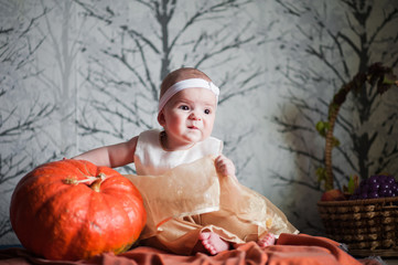 Mimicry of a small child. A little girl in a beautiful dress and a pumpkin. Child and pumpkin, autumn photography.