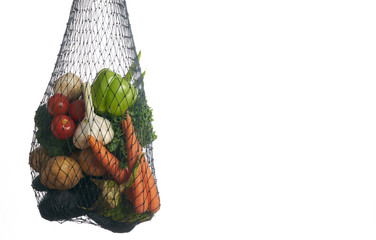 Assorted vegetables in mesh grocery bag isolated over white background with copy space.  Detox and...