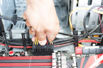 Men hand hold connect power plug and cable to power conection on motherbord in computer ATX case