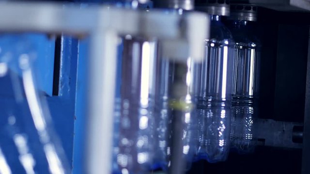 New PET water bottles leaving the heating chamber after production. 4K.