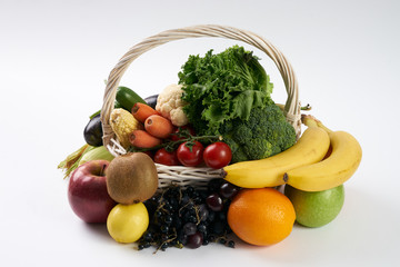 Close-up composition with raw vegetables and fruit in white wicker basket isolated on white background. Detox and healthy eating concept. Vegetarian food.