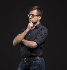Young pensive man portrait of a confident businessman on a black background. Ideal for banners, registration forms, presentation, landings, presenting concept.
