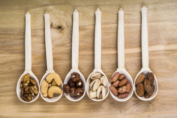 Nuts in a wooden spoons on a  wooden table.
