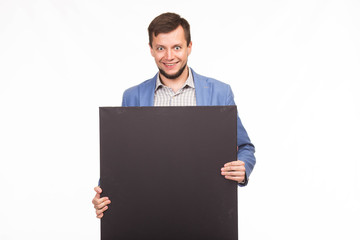 Young happy man portrait of a confident businessman showing presentation, pointing paper placard gray background. Ideal for banners, registration forms, presentation, landings, presenting concept.