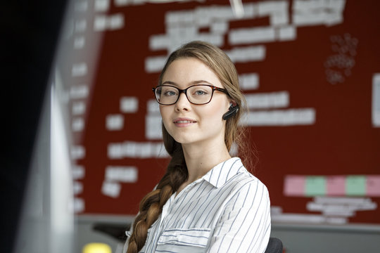 Portrait of young woman in office wearing headset