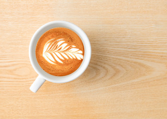 Time for espresso. Above capture of white coffee cup with tree shape latte art on wood table at cafe
