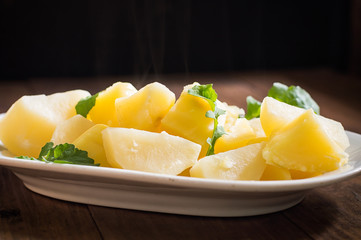 Boiled potatoes with rocket salad. Wooden background. Top view. Close-up