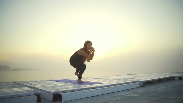 flexible woman slim black wear do yoga eagle pose sunrise fog rapid slow motion