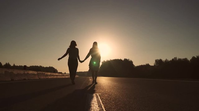 Two girls are walking on the road at dawn