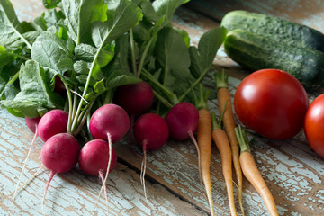 Fresh farm vegetable- radish, cucumber, tomato, carrot on wooden rustic background, side view