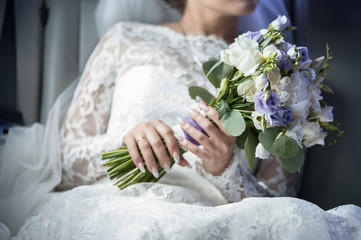 Obraz na płótnie Canvas Bouquet of flowers from white and lilac astromelia and freesias in the hands of the bride macro