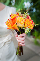 A bouquet of orange roses and a wedding koala, in the hands of the bride. Macro