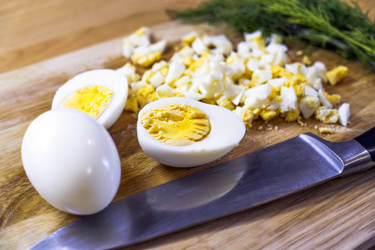 Eggs on the board. Eggs cut with a knife. Dill, egg and a knife.