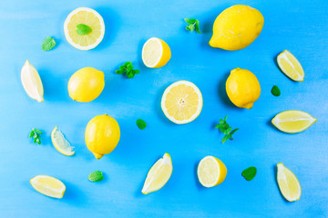 Fresh lemon citrus fruits slices with mint leaves pattern on blue bakground